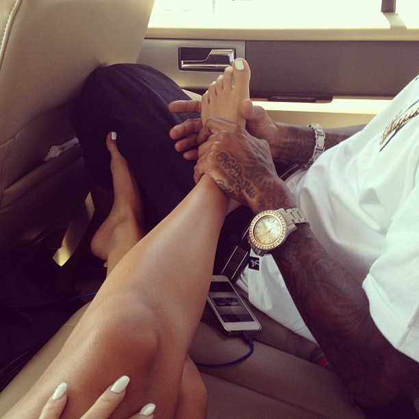 Getting a foot massage in the back of a luxury vehicle, while trying to shield her eyes from the brightness of his watch.