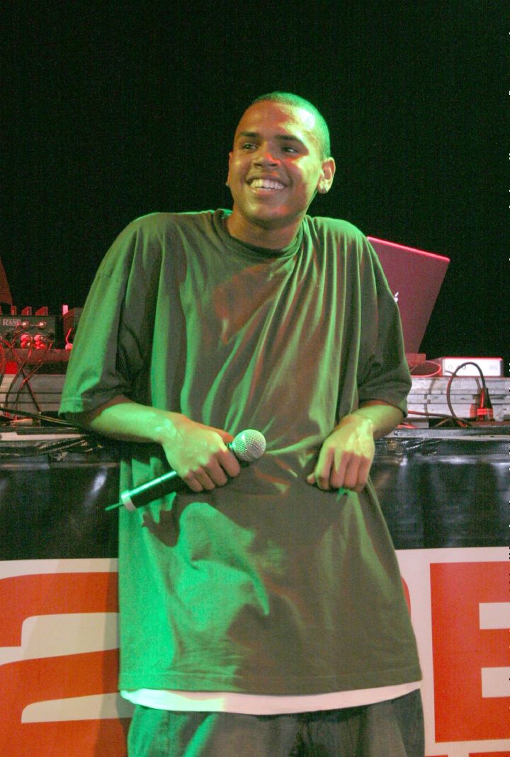 Chris Brown wears a super tall baggy t-shirt while performing with a huge smile on his face.
