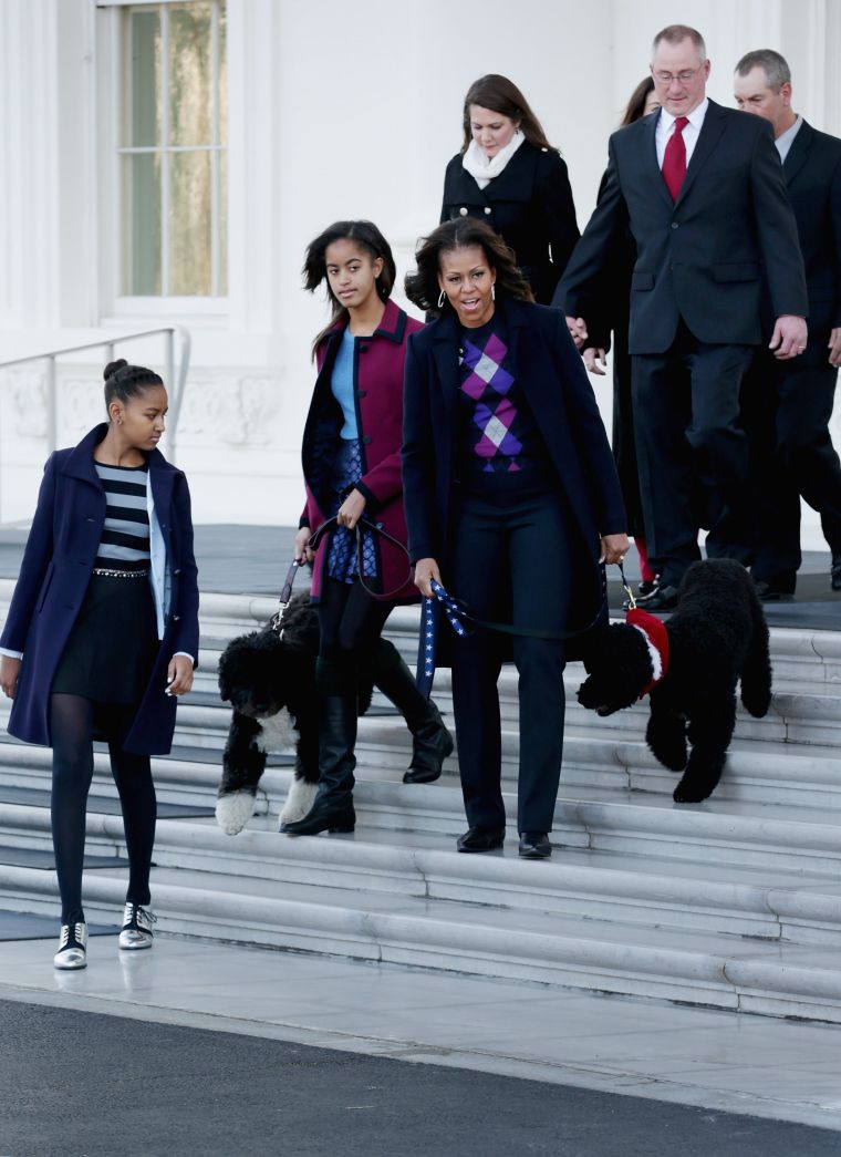 The ladies of the White House cover up in jewel-toned coats while walking Bo.