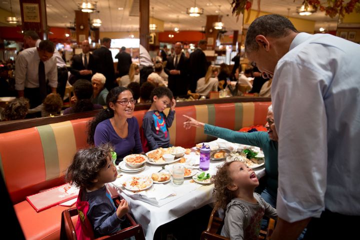 Looks like President Obama is interrupting dinner at Brooklyn’s iconic restaurant Juniors. But this little girl doesn’t mind.
