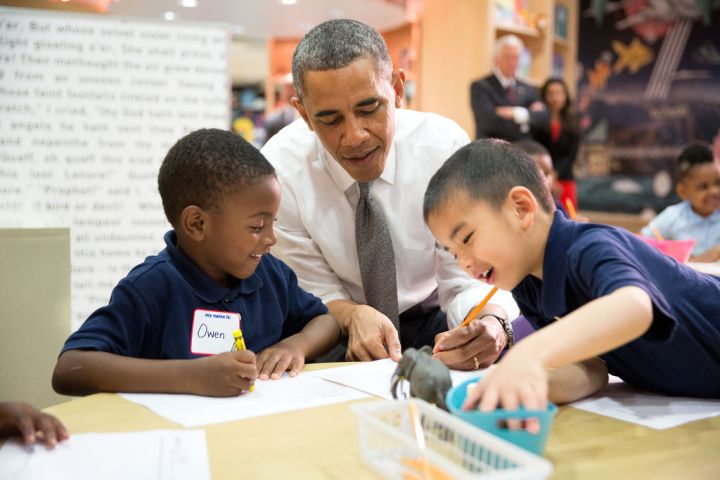 Students help Obama during a literacy lesson at an elementary school.