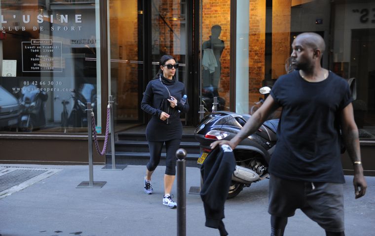Kanye watches out for traffic as he and Kim cross the street.