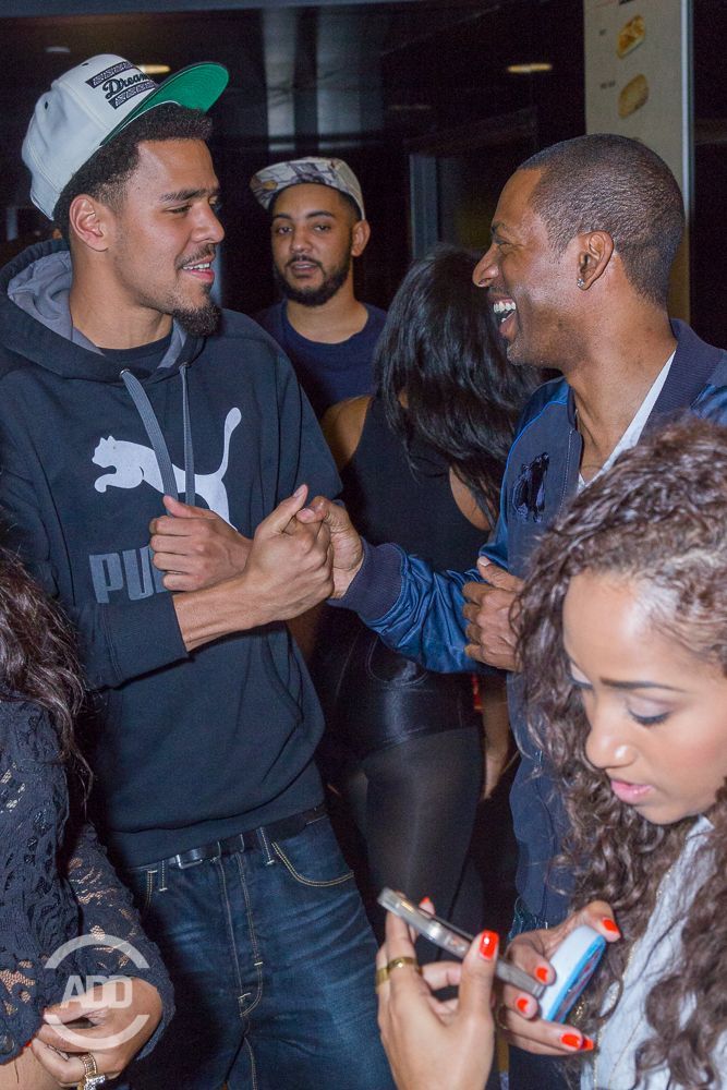 J. Cole and Tony Rock dap each other up.