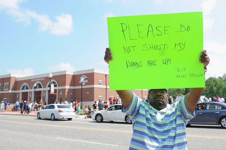 A man holds a sign in honor of Michael Brown, the unarmed teen who was killed by Ferguson police on Saturday, August 9, 2014.