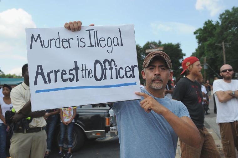 A protestor holds up a sign calling for the arrest of the officer who shot Michael Brown.