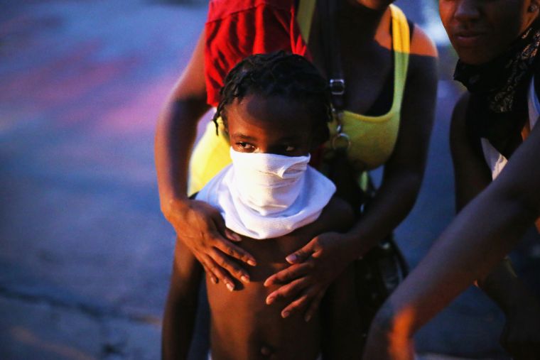 A child covers his face with a shirt after police fire tear gas into a crowd.