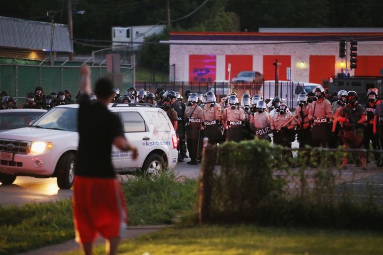 Police watch as demonstrators protest the shooting of unarmed teen Michael Brown.