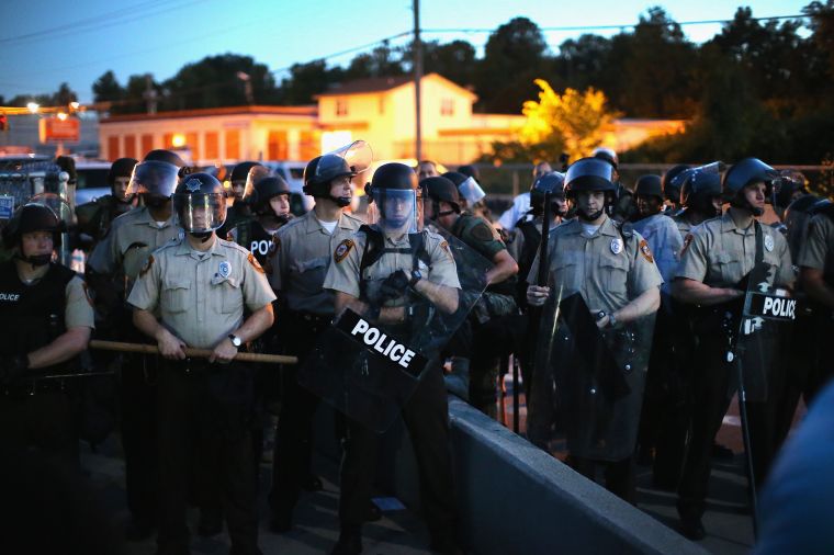 Ferguson police line up with riot gear where protesters are demonstrating.