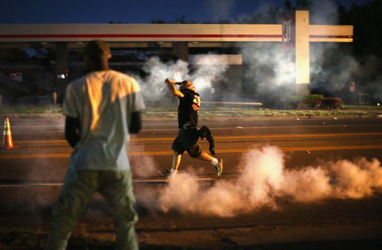 Ferguson police throw tear gas to disperse crowds protesting in the streets.