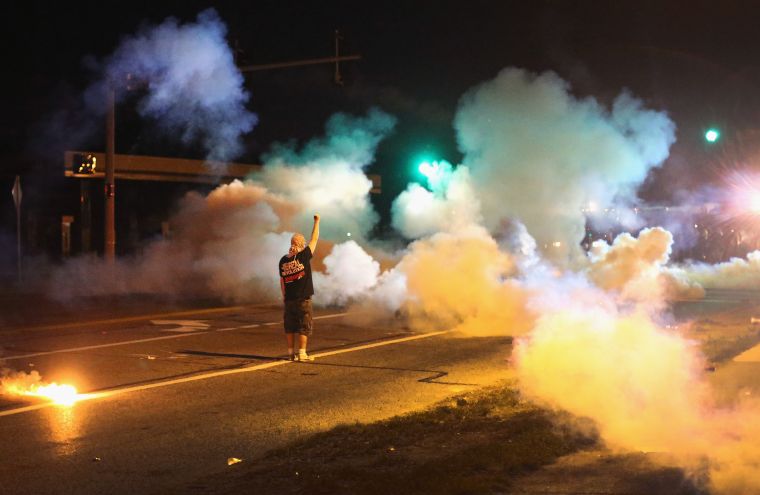 Protester stands his ground as police throw tear gas.