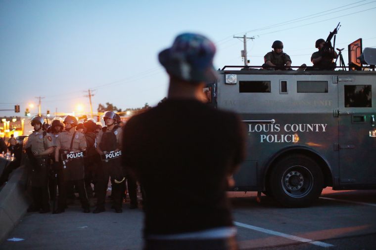 Police stand and watch protesters.