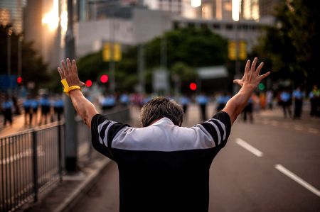 A man holds his hands in the air during protests in Hong Kong.