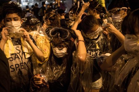 Demonstrators decked out in goggles, bandanas, t-shirts and plastic wrap gear up to face police lobbing tear gas at the crowd.