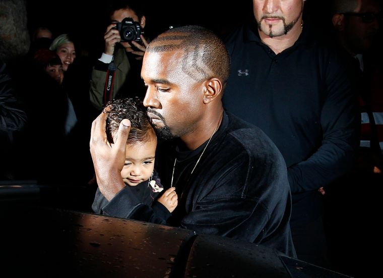 Kim Kardashian, Kanye, & North West attend the Balenciaga show during Paris Fashion Week.