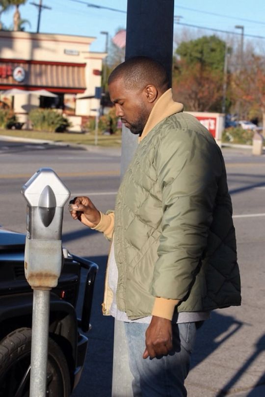 Kanye West putting quarters into the meter.