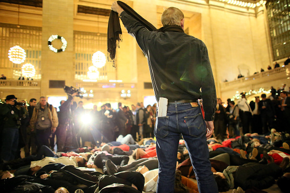 A man symbolically chokes himself with a scarf during a protest in Grand Central Station.