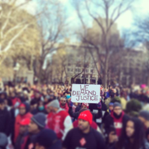 A protestor holds up a focused ‘We Demand Justice’ sign