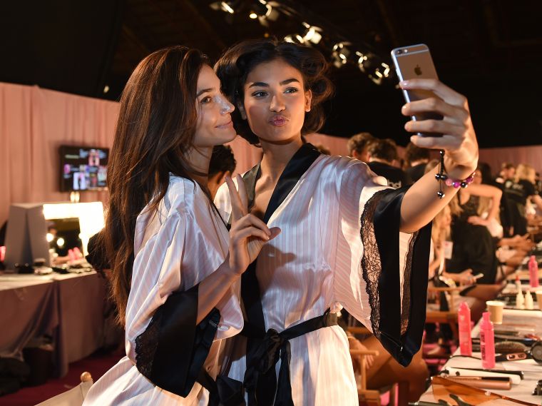 Izabel Goulart and Lais Ribeiro pose for a selfie backstage in hair and makeup at the Victoria’s Secret Fashion Show 2014 in London.