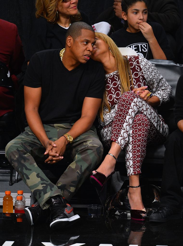 Bey tells her man a secret while sitting courtside.