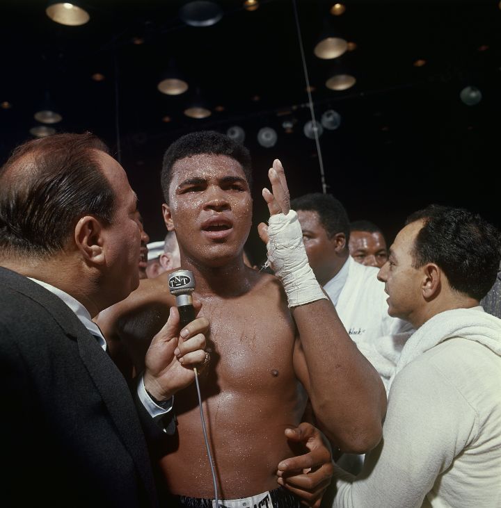 FEBRUARY 25, 1964: Cassius Clay (aka Muhammad Ali) talks into a reporter’s mic after defeating Sonny Liston, not pictured in a World Heavyweight Title fight February 25, 1964 at Convention Hall in Miami, Florida.