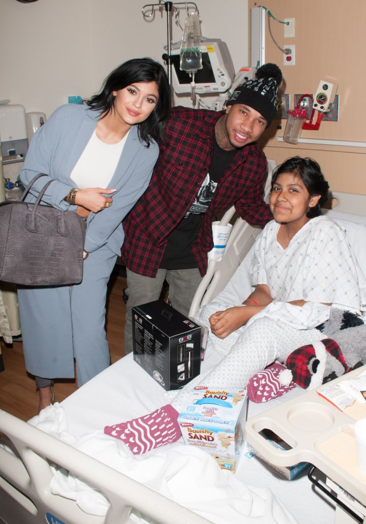 Kylie and Tyga smile with a fan at a children’s hospital.