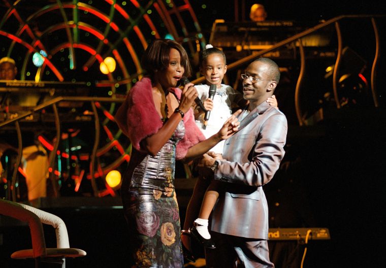 Whitney Houston with her daughter Bobbi Kristina Brown and husband Bobbi Brown onstage during a concert on July 16, 1999.