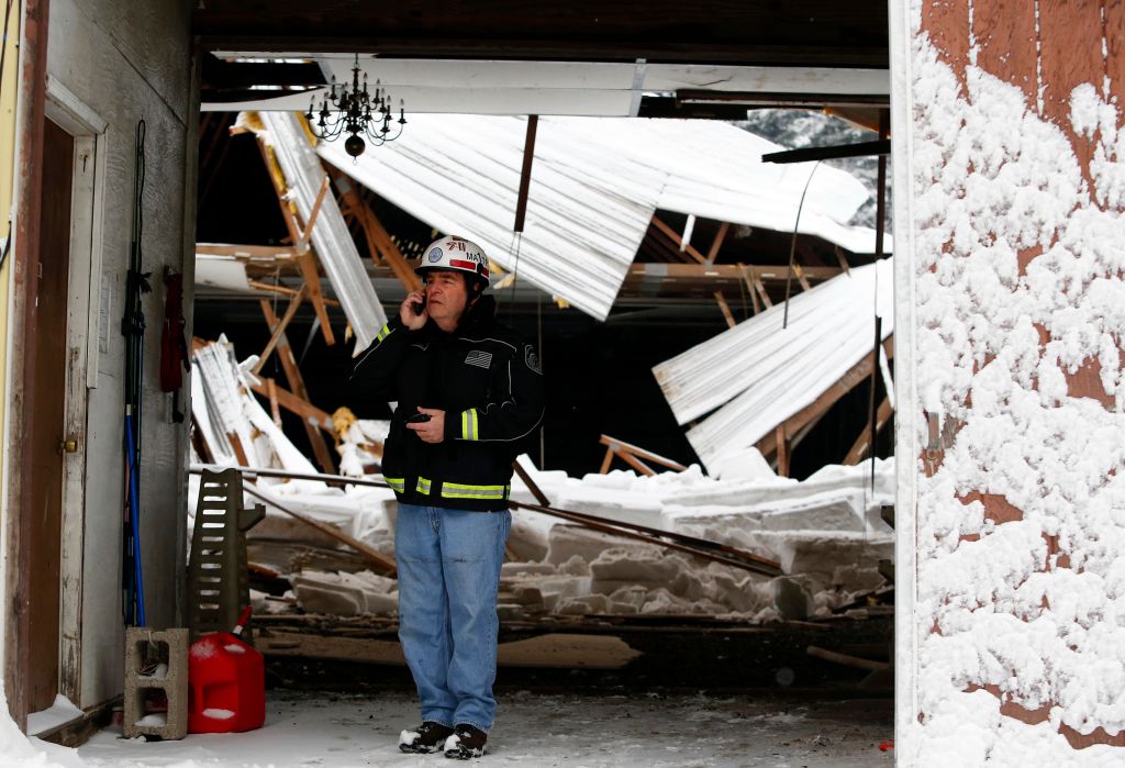 An official stands in front of a partial roof collapse