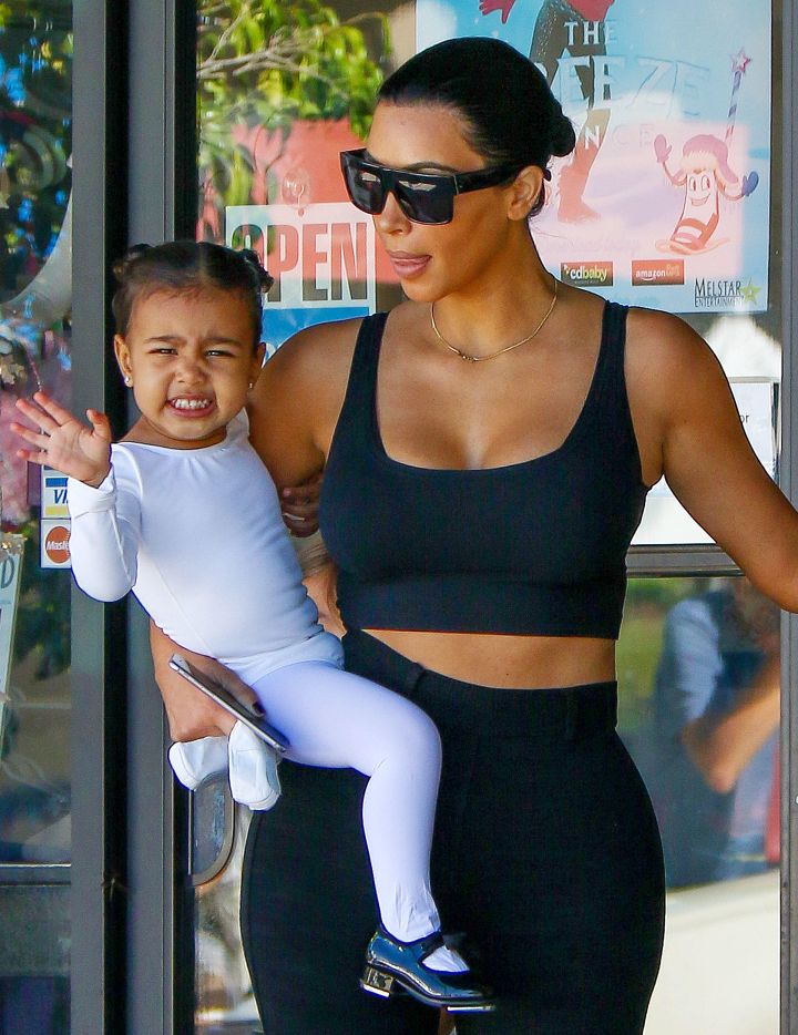 North shoos the paparazzi away from her mom.