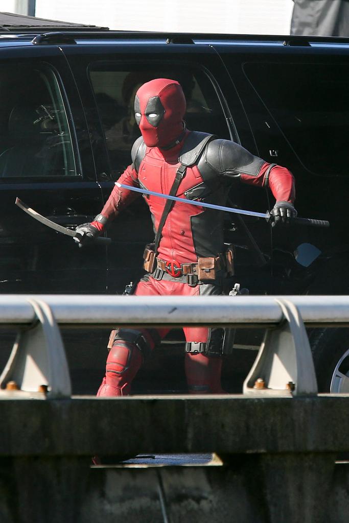 Ryan Reynolds, in costume as 'Deadpool' films a fight scene using two katana swords.
