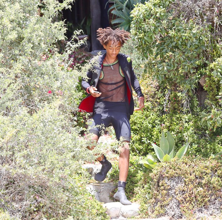 Jaden Smith running down a grassy hill in a see-through mesh shirt.