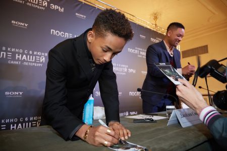 Jaden Smith signing his name on a picture of himself.