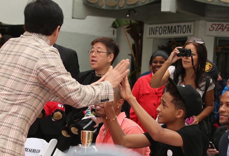 Jaden Smith playing patty cake with Jackie Chan.