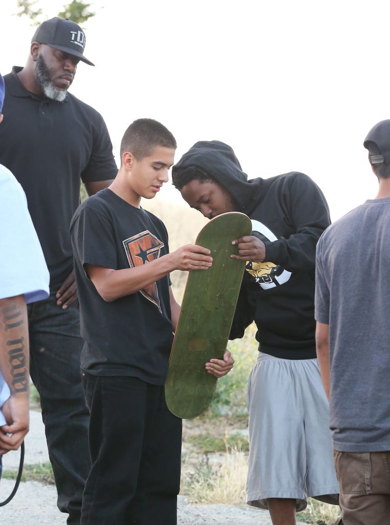 Kendrick Lamar took the time to sign a fan's skateboard while shutting down Los Angeles for a music video shoot.
