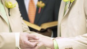Man placing ring on another man's finger