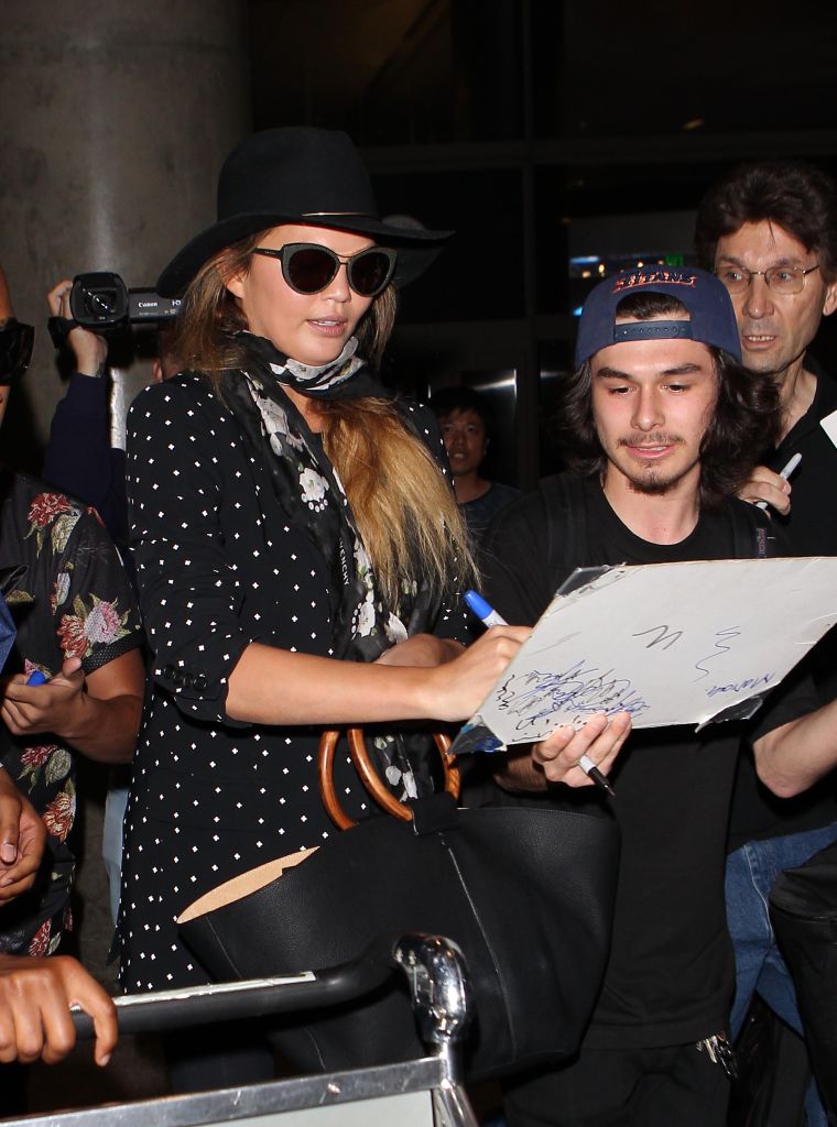An incognito Chrissy Teigen greets fans at LAX.