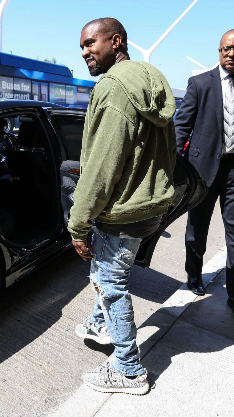 Look at that! Kanye West cracked a small smile for the paparazzi as he got into his ride at LAX.