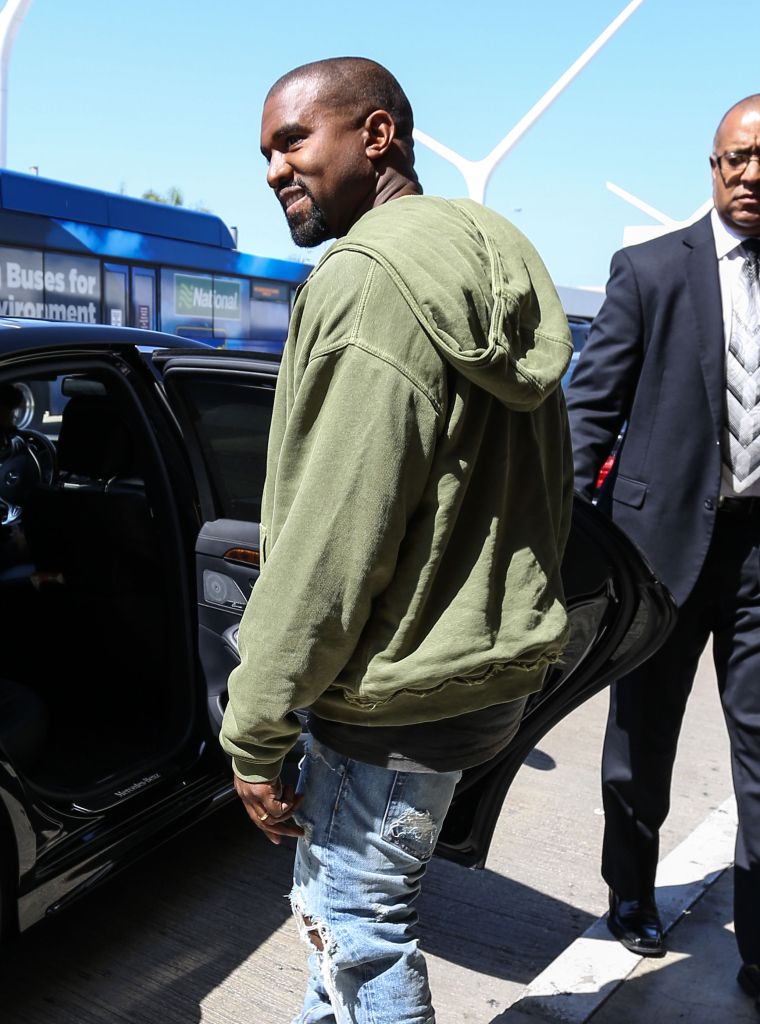 Look at that! Kanye West cracked a small smile for the paparazzi as he got into his ride at LAX.