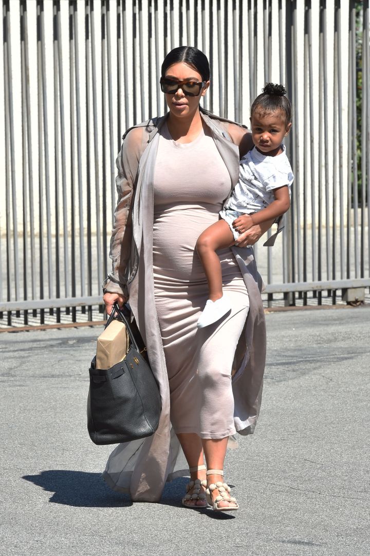 Kim Kardashian showed off her growing bump while heading to a party with baby North on her side.
