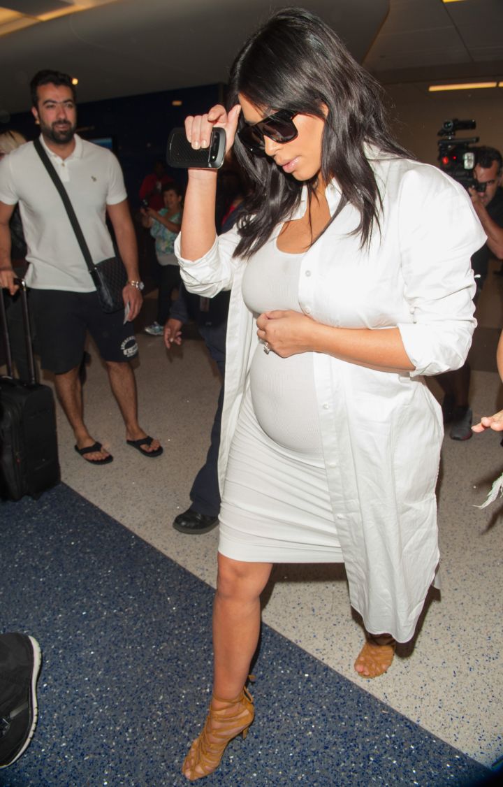 Kim Kardashian flaunts her belly full of Yeezus as she walks through the airport.