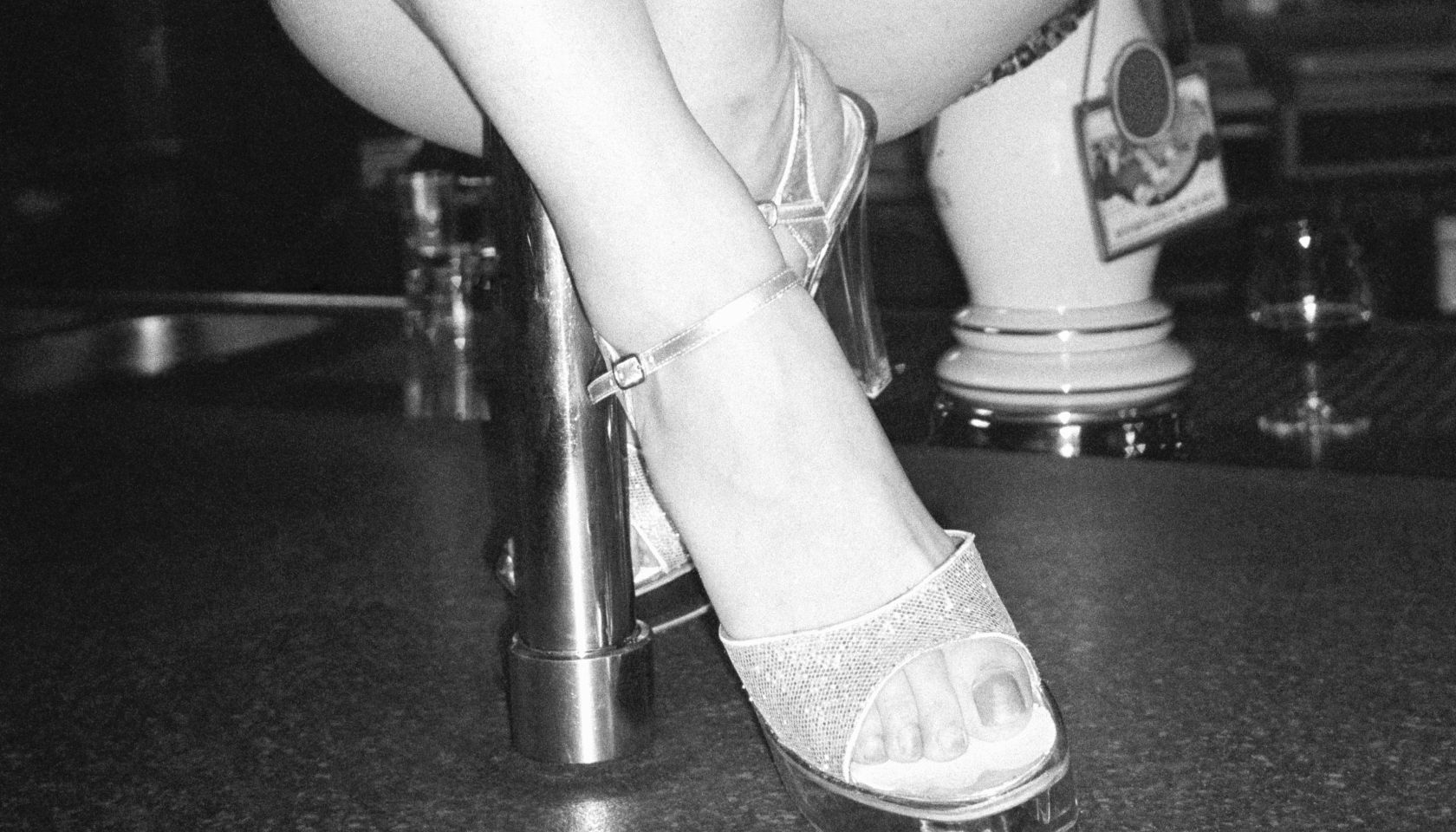 Woman pole dancing on bar counter