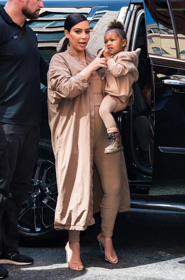 North West looks ready for action in her mommy, Kim Kardashian’s arms.