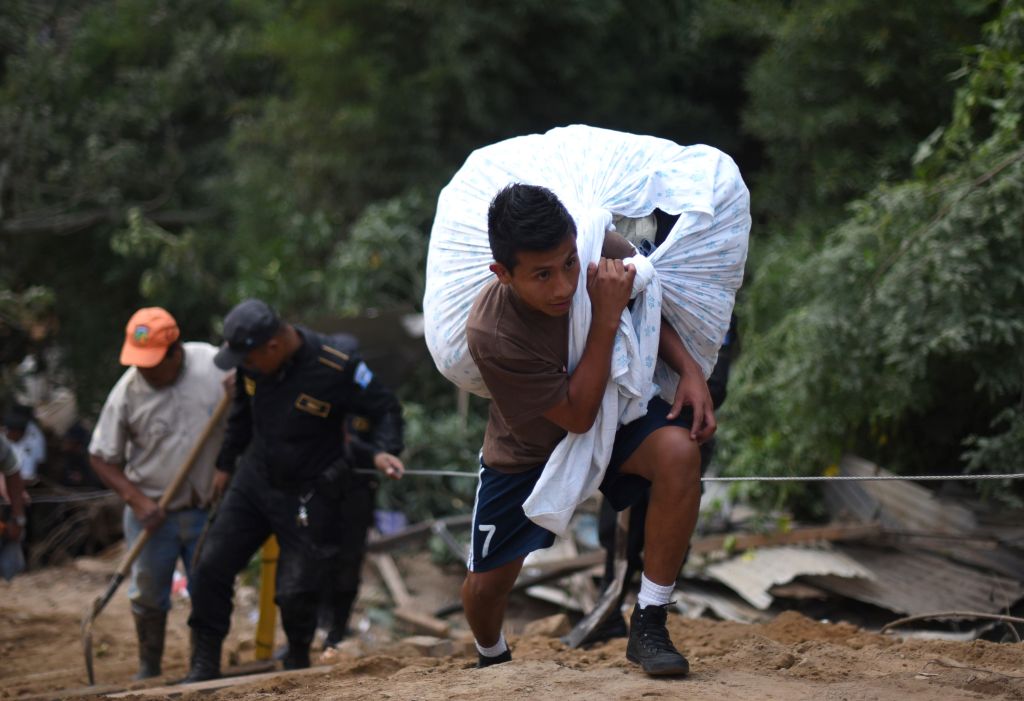 young man carries his belongings after a landslide late Thursday, following heavy rains, covered part of the village of El Cambray II, in Santa Catarina Pinula municipality