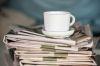 Stack of newspaper and coffee cup