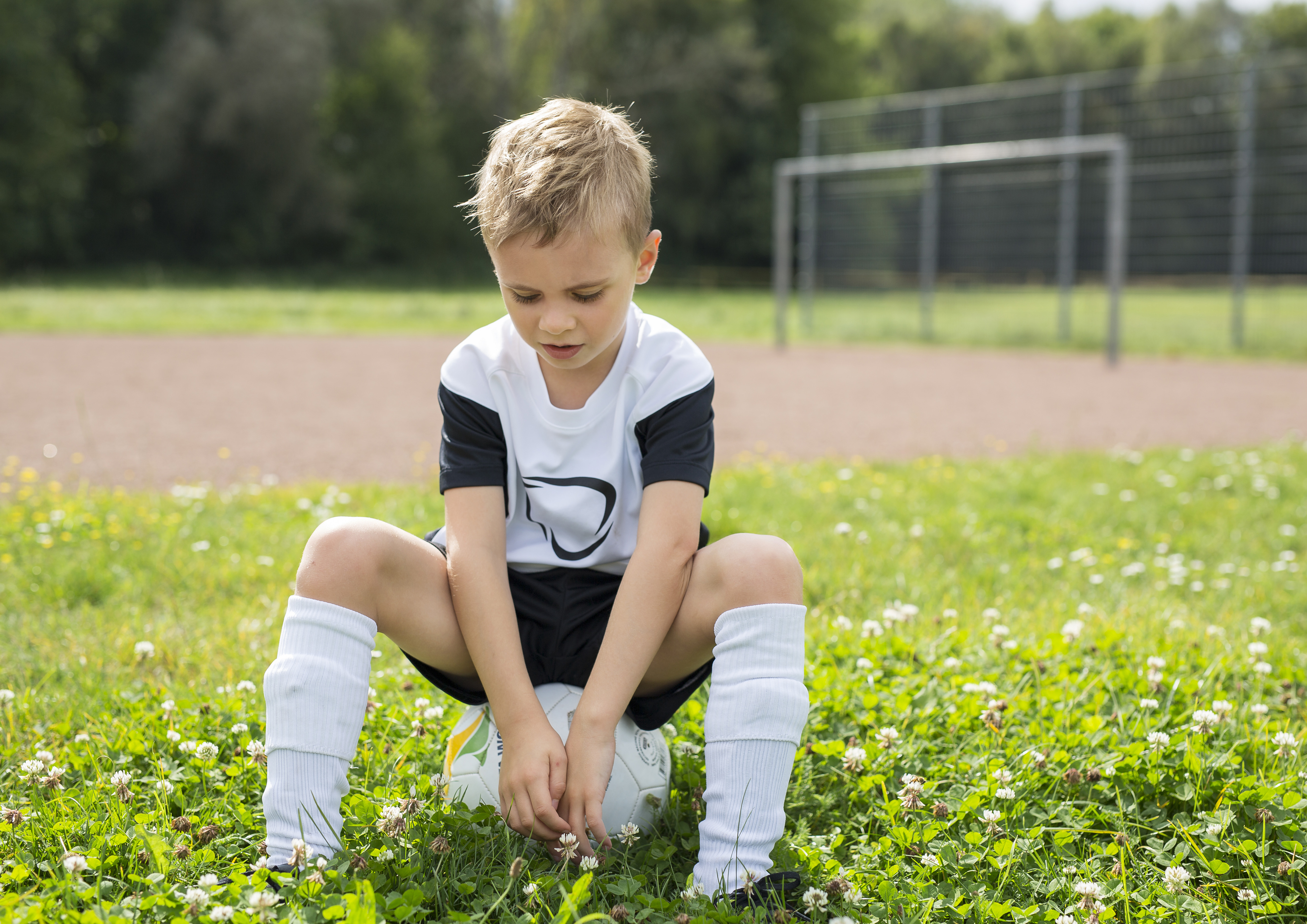 Serious boy sitting on football