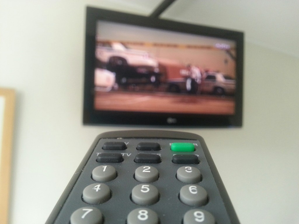 Close-Up Of Remote Control Against Television Set At Home