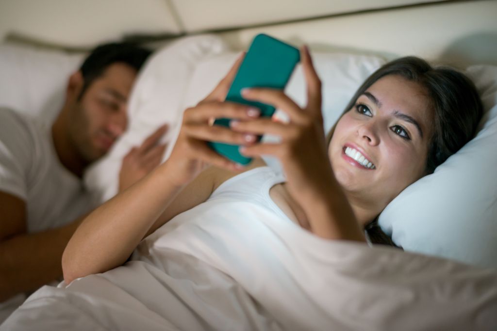 Woman social networking in bed on her phone
