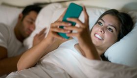 Woman social networking in bed on her phone