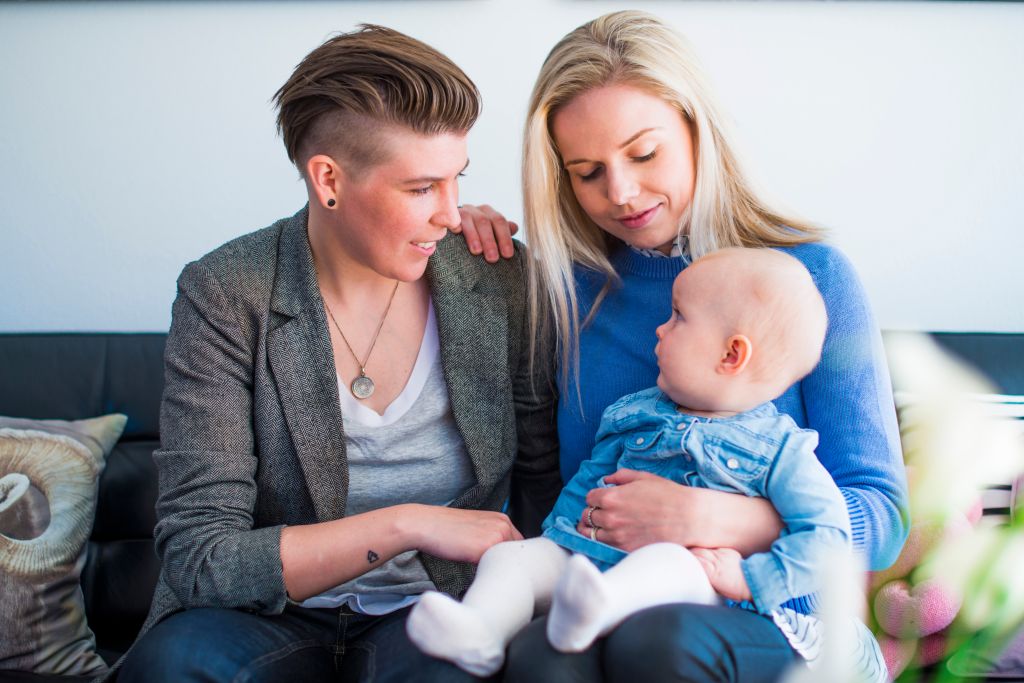 Happy young lesbian couple with baby at home