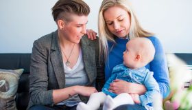 Happy young lesbian couple with baby at home