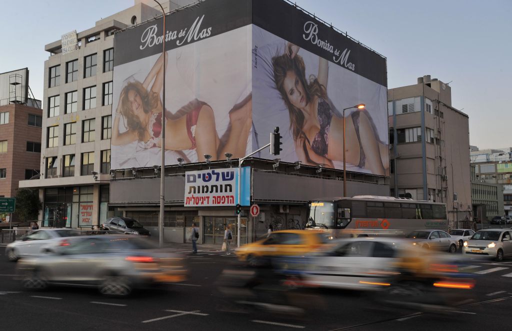 Cars drive past a billboard featuring Is